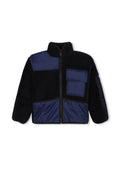 Fleecegefütterte Jacke mit marineblauen Nylonpaneelen und Taschen, schwarzem Körper, hohem Kragen, durchgehendem Reißverschluss und einem Markenlogo am Ärmel.