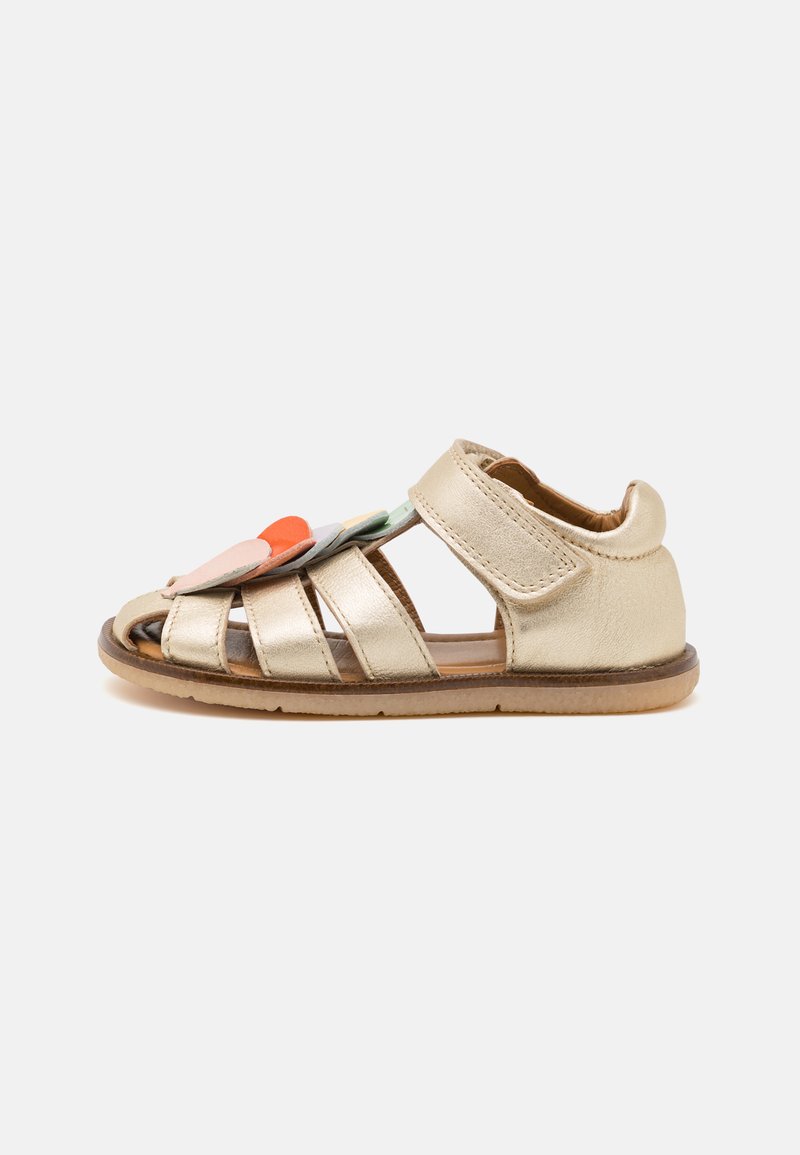 Goldene Leder-Sandalen mit mehreren Riemen, einem verstellbaren Klettverschluss und dekorativen Filzblumen in Orange, Blau und Grün.