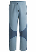Hellblaue Sweatpants mit einer Mischung aus helleren und dunkleren blauen Stoffpaneelen, elastischem Bund mit Kordelzug und Kontrastnähten.