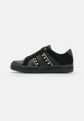 Schwarzer Sneaker mit Schnürung, strukturierten Seitenpanelen und goldenen quadratischen Nieten auf weißem Hintergrund, zeigt die äußere Seitenansicht.