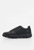 Schwarze Slipper aus strukturiertem Leder mit glatter Oberfläche, ausgestattet mit einer Gummisohle und elastischen Seiteneinsätzen für Flexibilität.