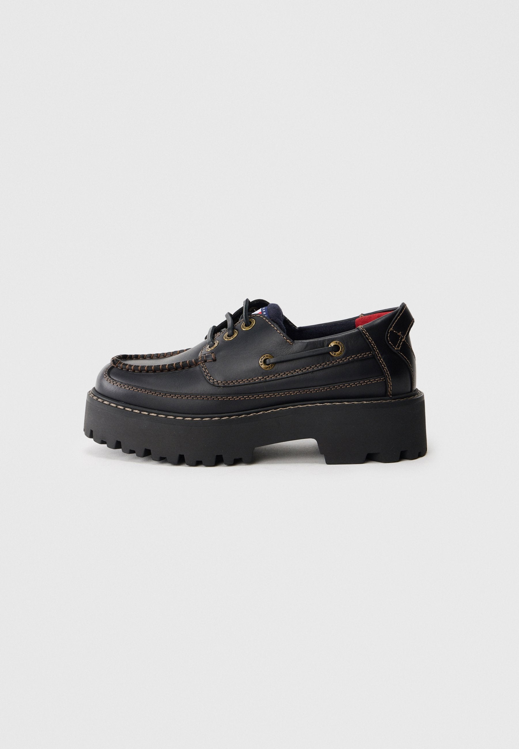 Schwarze Lederschuhe mit abgerundetem Design, dickem schwarzen Plateausohle, dekorativer Stickerei und Messingösen für die Schnürsenkel.