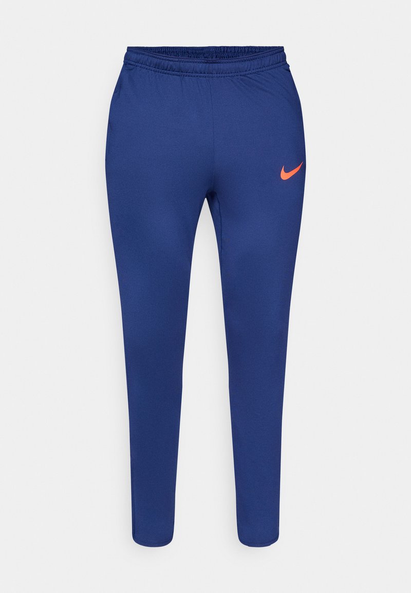 Marineblaue Slim-Fit-Sporthosen mit elastischem Bund und orangefarbenem Nike-Swoosh am rechten Oberschenkel vor weißem Hintergrund.