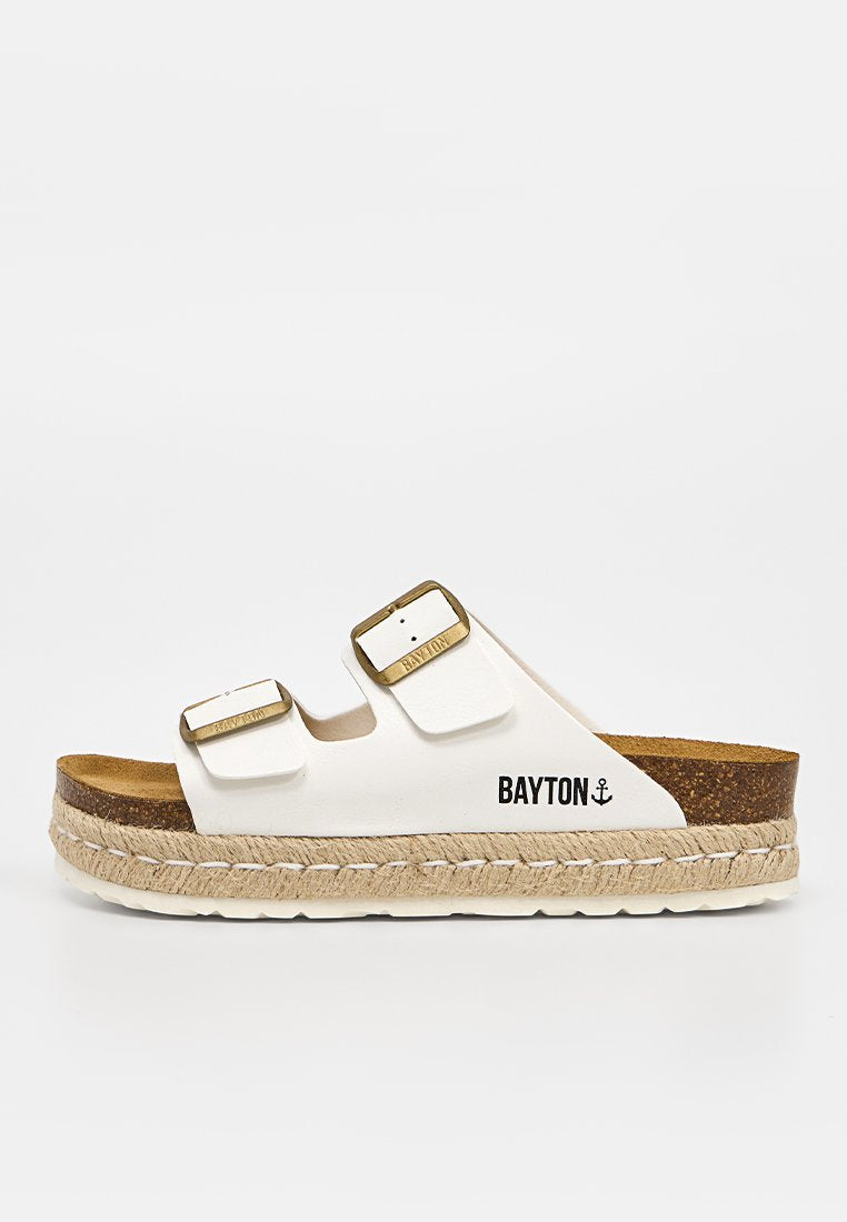 Weißer Slide-Sandalette mit zwei verstellbaren goldenen Schnallen, Kork-Fußbett, Sohle mit Tau-Details und "BAYTON"-Branding mit Ankersymbol an der Seite.