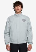 Hellgraue Bomberjacke mit Stehkragen, gerippten Bündchen und Saum, mit einem runden Logo auf der linken Brust und seitlichen Taschen.