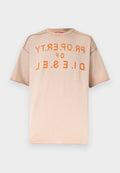Beiges Kurzarm-T-Shirt mit orangefarbenem, distressed bedrucktem Text "PROPERTY OF DIESEL", der spiegelverkehrt über der Brust verläuft.