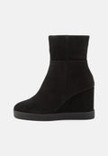 Schwarze Wildleder-Wedge-Stiefelette mit runder Zehenpartie und mittelhohem Plattformsohle, nahtloses Oberdesign, seitlich auf weißem Hintergrund betrachtet.