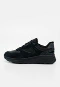Schwarzer Low-Top-Sneaker mit Wildleder- und Stoffeinsätzen, dicker Sohle, schwarzen Schnürsenkeln und sichtbarem, plüschigem Futter am Kragen.