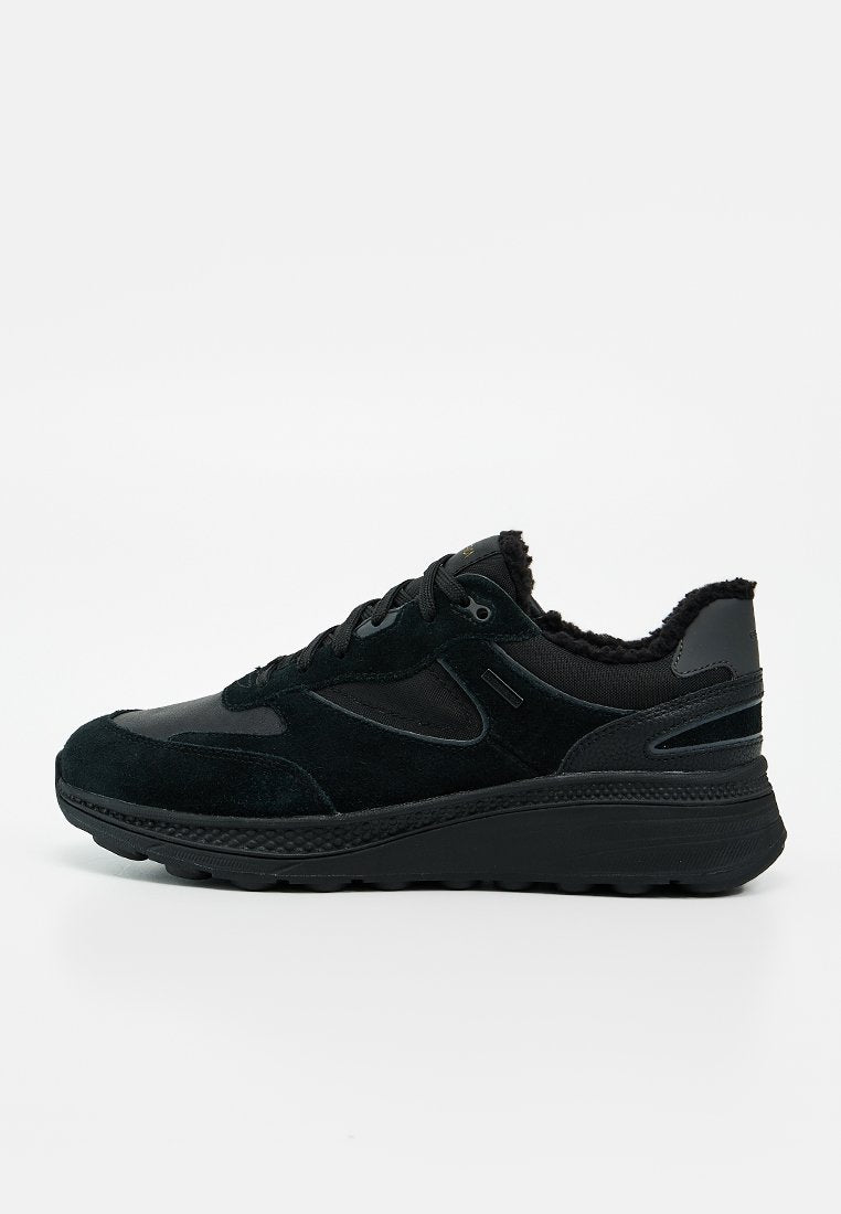 Schwarzer Low-Top-Sneaker mit Wildleder- und Stoffeinsätzen, dicker Sohle, schwarzen Schnürsenkeln und sichtbarem, plüschigem Futter am Kragen.