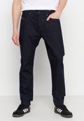 Dunkelblaue Jeans aus Denim mit geradem Schnitt, Fünf-Taschen-Design, vorderem Knopfverschluss und dezenten Nähten. Schwarze Sneakers mit weißen Streifen.