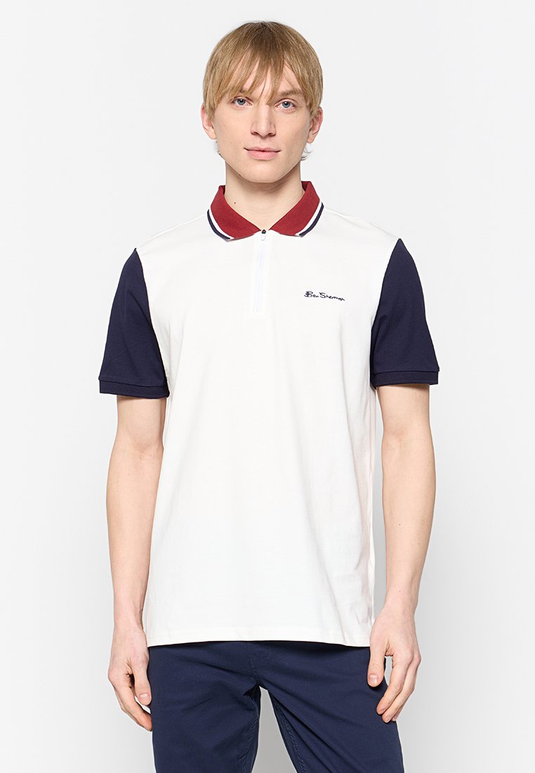 Polohemd in hellem Creme mit navyblauen kurzen Ärmeln und einem burgunderfarbenen Kragen. Verfügt über einen Viertel-Reißverschluss und ein dezentes Logo auf der Brust.