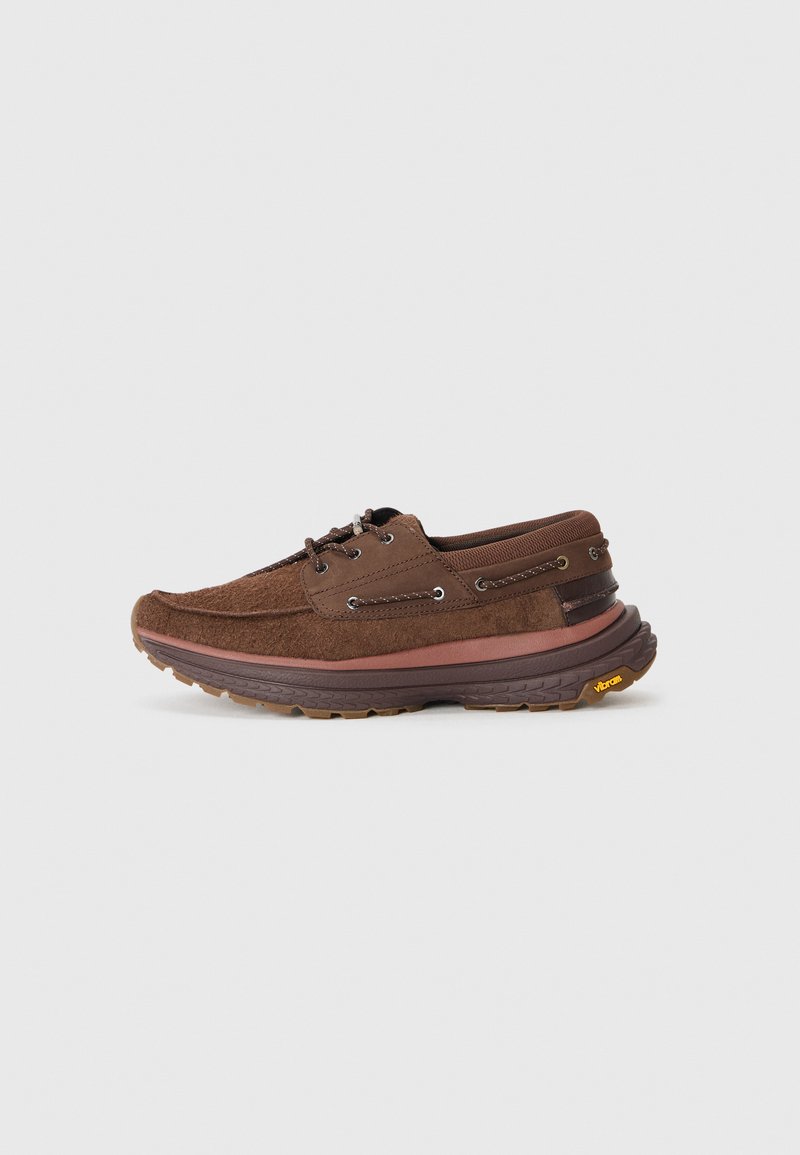 Braune Wildlederschuhe mit runder Zehenform, Schnürdesign, Vibram-Laufsohle und mehrschichtigen Akzenten an der Seite.