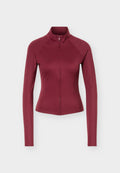 Eng anliegende bordeauxrote Jacke mit langen Ärmeln, hohem Kragen und Frontreißverschluss, vor einem einfarbigen hellen Hintergrund präsentiert.