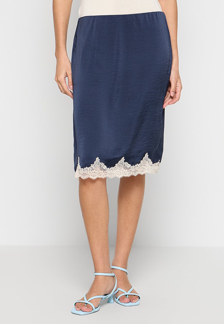 Marineblauer Satin-Bleistiftrock mit einer gewelltem cremefarbenen Spitzenkante. Er hat eine glatte Textur und eine taillierte Silhouette. Wird mit hellblauen Riemchensandalen getragen.