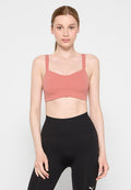 Rosenfarbener Bralette mit dünnen Trägern und V-Ausschnitt, aus glattem, dehnbarem Stoff. Kombiniert mit schwarzen, hochgeschnittenen Leggings.