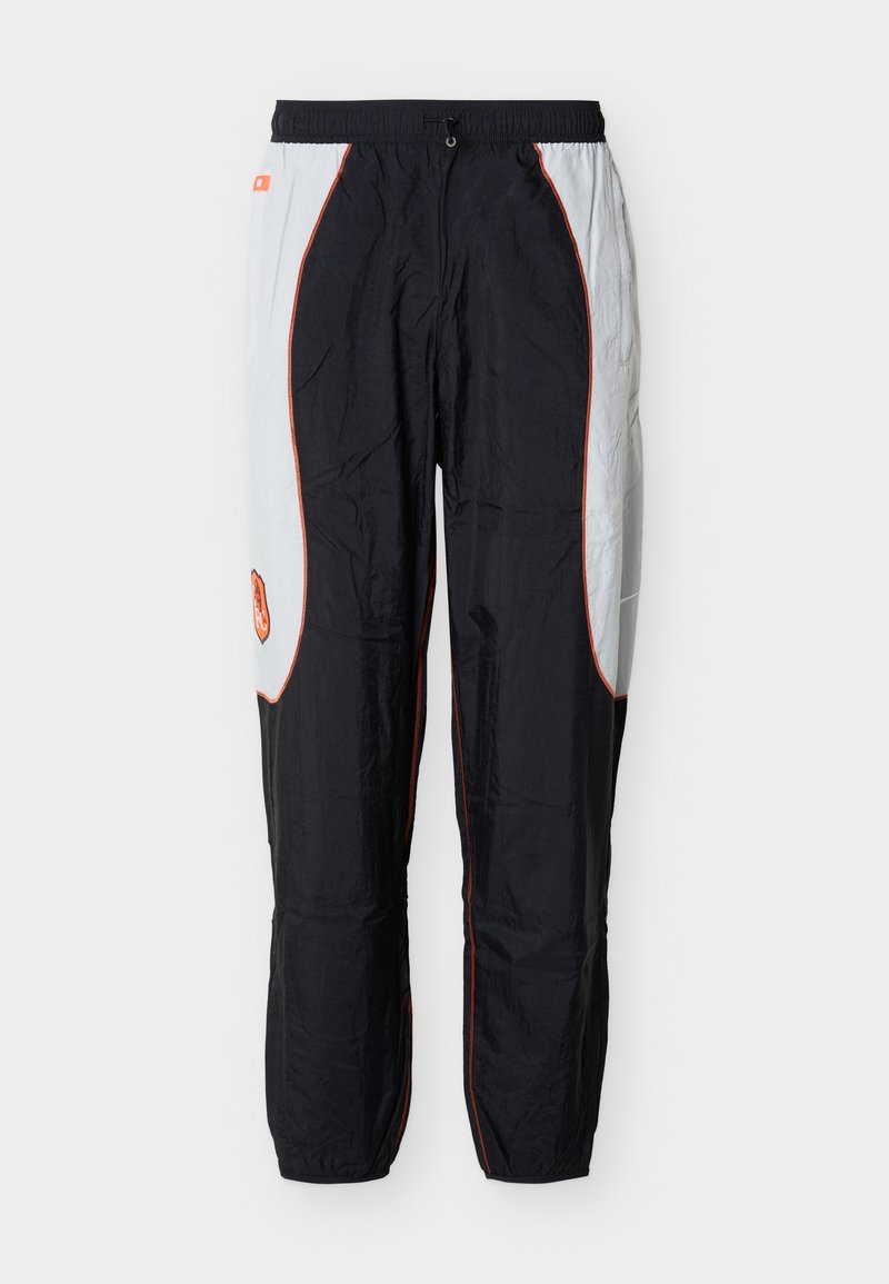 Schwarz-weiße Jogginghose mit orangenen Paspelierungen, elastischem Bund und einem kleinen orangenen Logo am linken Oberschenkel.