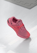 Rosa Sportschuh mit einem Mesh-Obermaterial und schwarzen Akzenten, strukturiertem Sohle und standardmäßiger Schnürung. Leichte Konstruktion ist deutlich erkennbar.