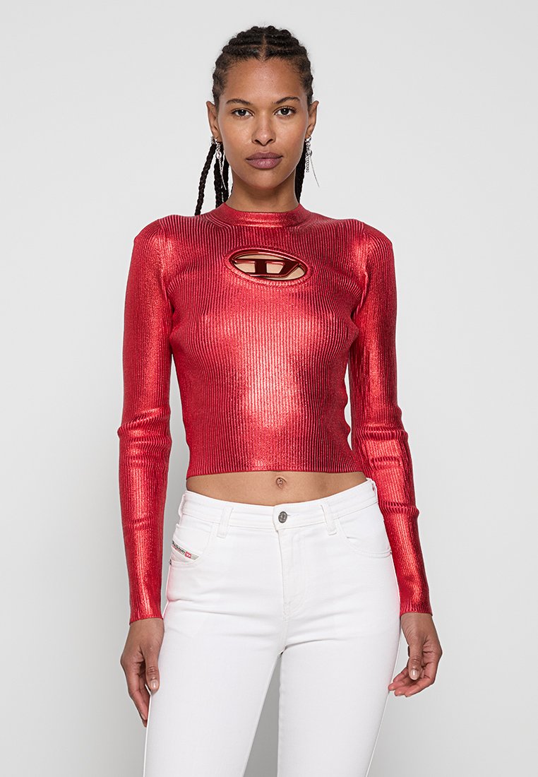 Roter metallic gestrickter Cropped-Top mit langen Ärmeln, versehen mit einem Schlüssel-Ausschnitt und geripptem Textur, kombiniert mit weißen, hoch taillierten Jeans.