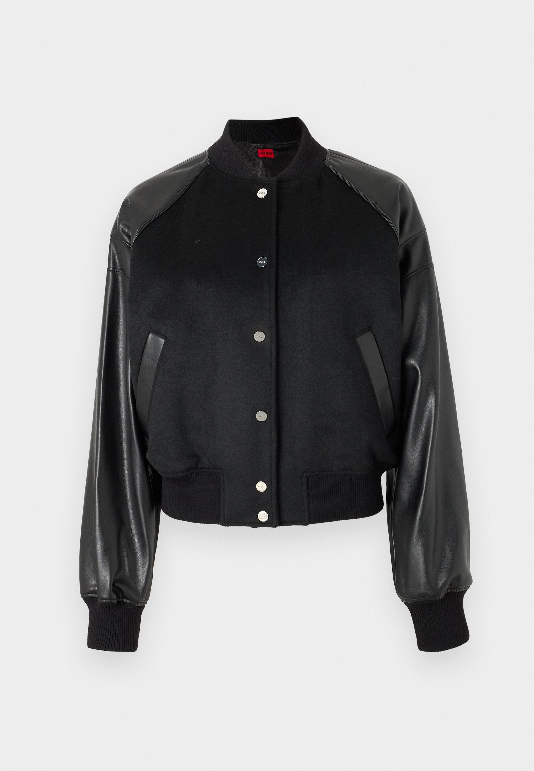 Schwarze Bomberjacke mit Wollkörper und Lederärmeln. Gerippte Bündchen und Saum. Druckknopfverschluss. Zwei seitliche Taschen für Nutzen.