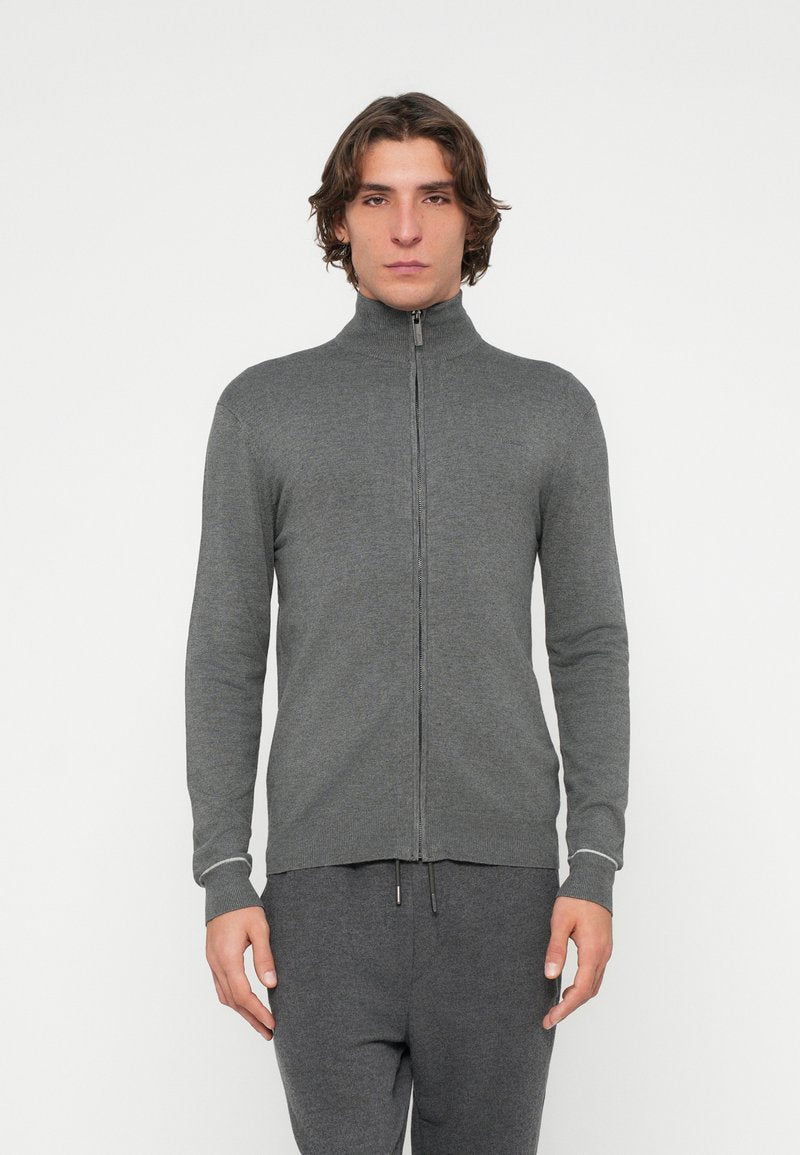 Grauer Pullover mit Reißverschluss und hohem Kragen, aus weichem Material. Mit langen Ärmeln und eng anliegendem Schnitt, ergänzt durch kontrastierende Blenden an den Bündchen.