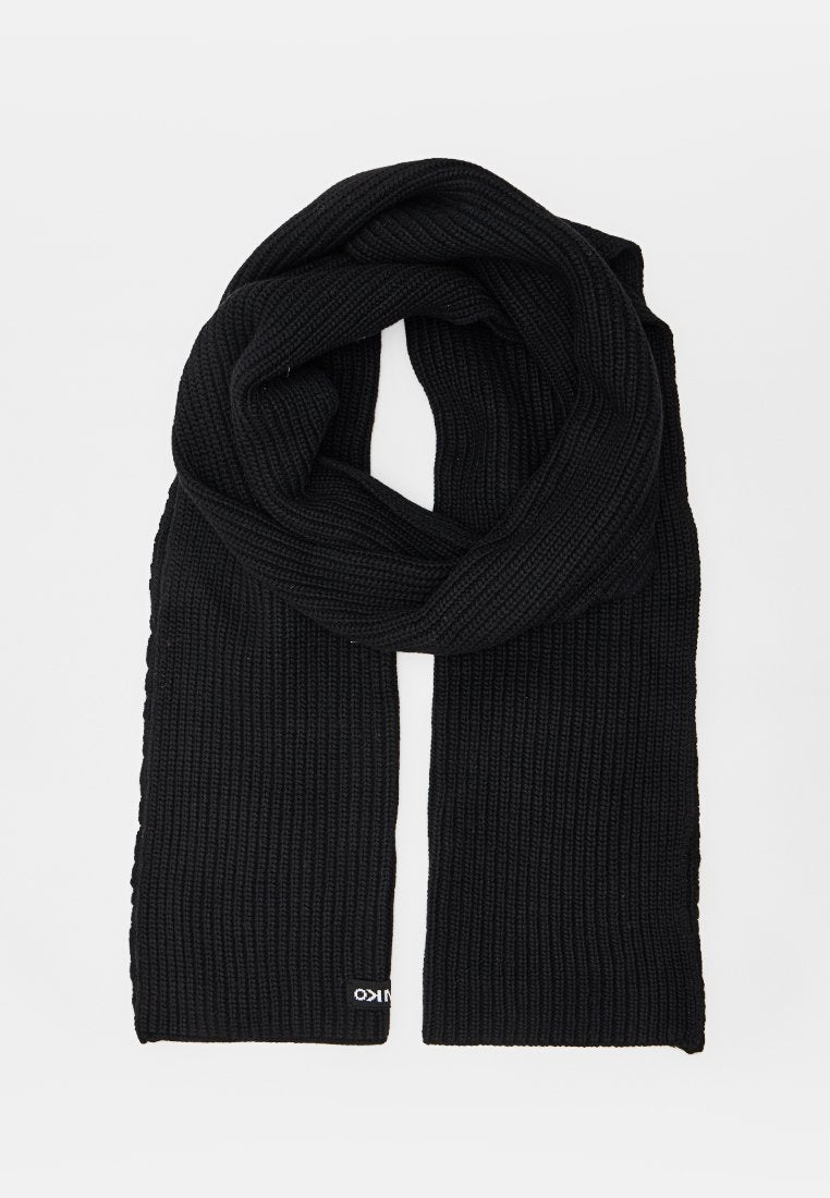 Schwarzer gestrickter Schal mit geripptem Muster, zusammengefaltet mit herabhängenden Enden, auf weißem Hintergrund präsentiert.
