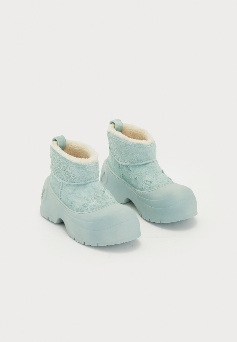 Hellblaue Winterstiefel mit dicken Gummisohlen und Fleece-Futter, ausgestattet mit Zuglaschen und strukturiertem Wildlederobermaterial für kaltes Wetter.