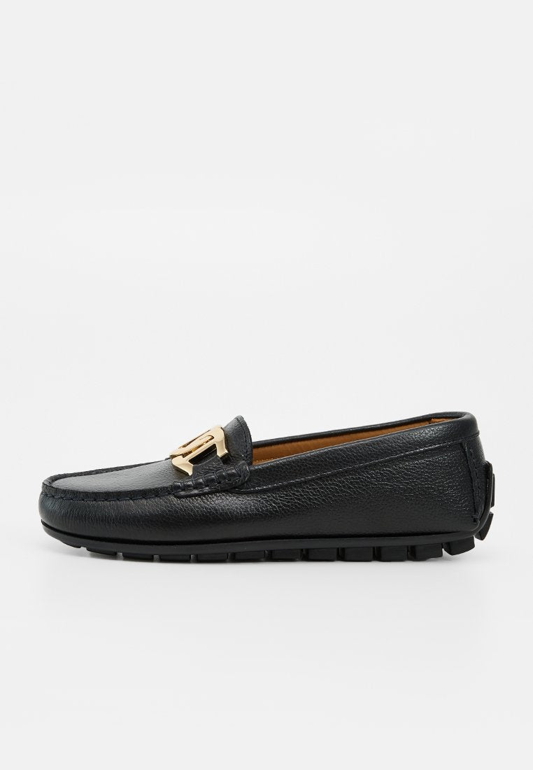 Schwarzer Lederloafer mit strukturierter Sohle und goldenem Metall-Schnallendetail oben, seitlich auf weißem Hintergrund gesehen.