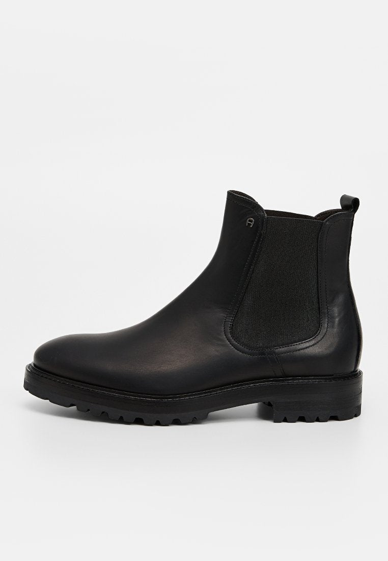 Schwarze Chelsea-Stiefel aus Leder mit elastischen Seitenteilen, abgerundeter Spitze und einer strukturierten Gummisohle. Mit einer Zuglasche an der Rückseite.