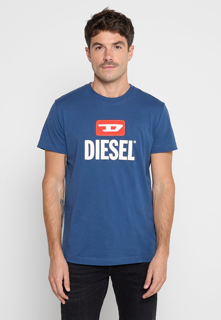 Blaues Baumwoll-T-Shirt mit einem roten und weißen "DIESEL"-Logo in fetter Schrift auf der Vorderseite. Kurze Ärmel und runder Halsausschnitt.