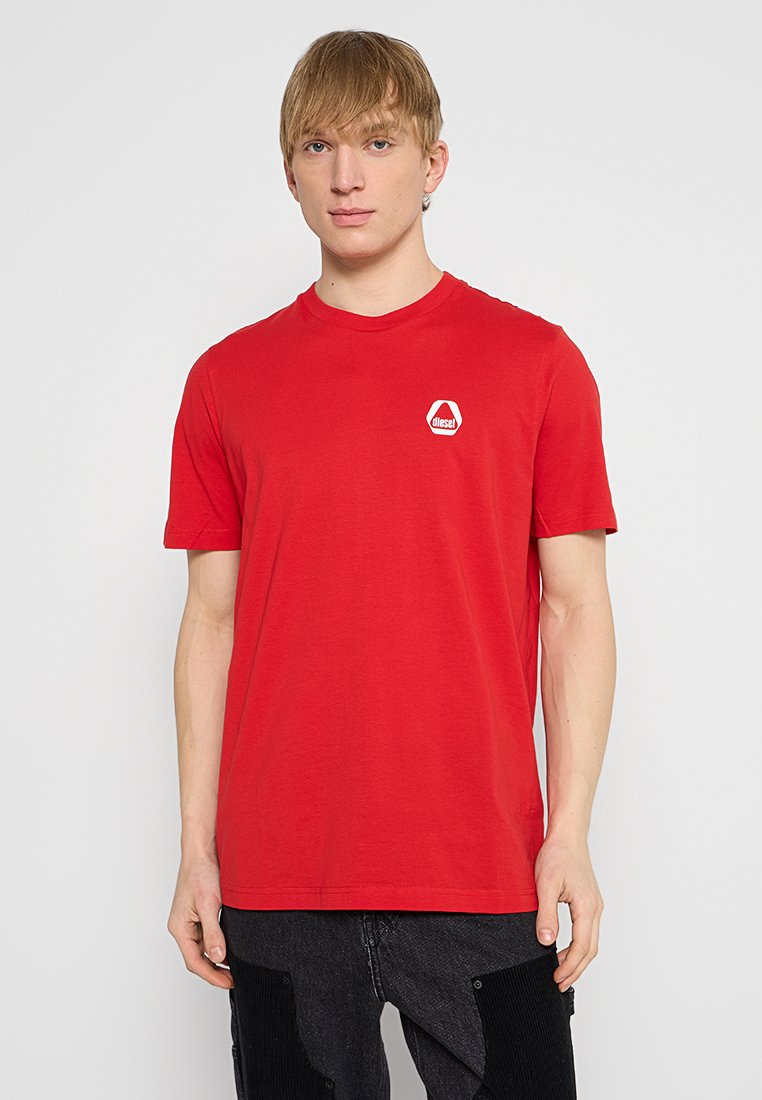Rotes Baumwoll-T-Shirt mit kurzen Ärmeln, Rundhalsausschnitt und einem weißen, hexagonalen Logo auf der linken Brust. Einfaches Design, leichtes Material.