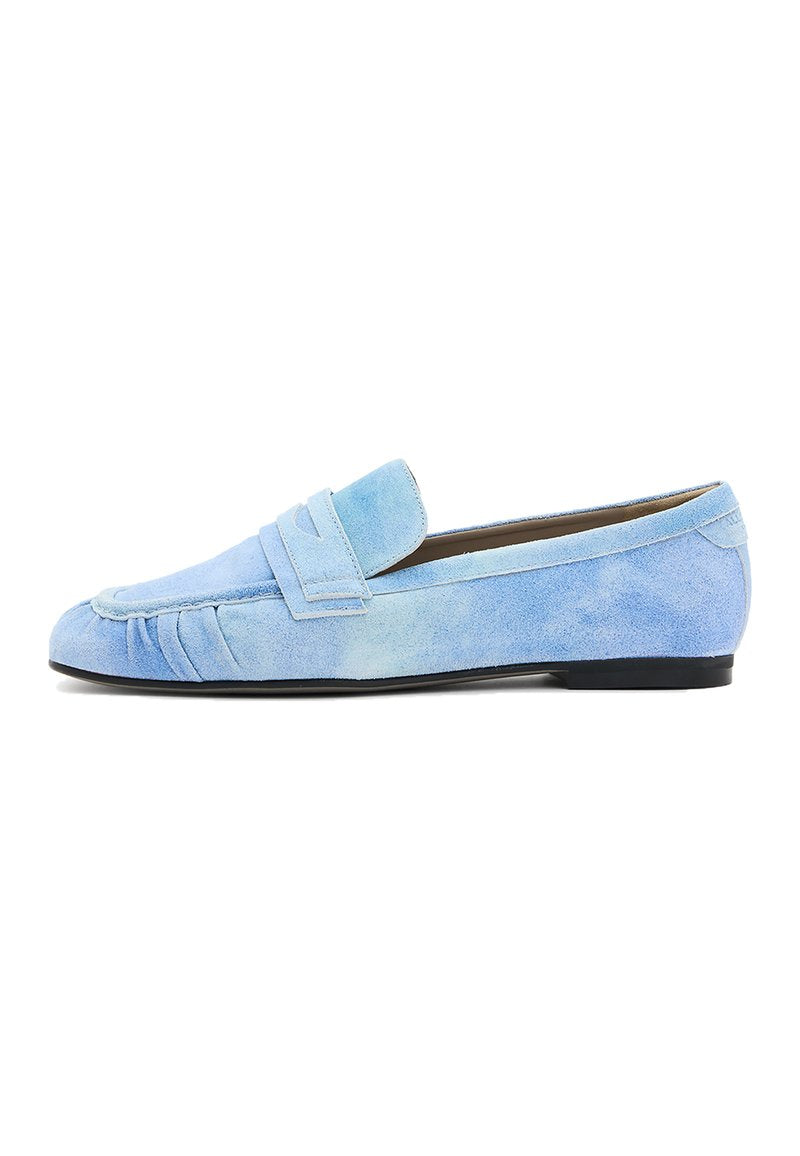 Blauer Wildleder-Loafer im Mokassin-Stil, mit gesticktem Detail an der Zehe und einer flachen schwarzen Gummisohle.