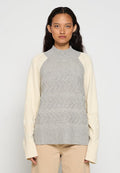Grau und cremefarbenes Sweatshirt mit hohem Kragen, strukturiertem Zickzackmuster auf dem Oberteil und gerippten Bündchen mit Zopfstrickdetails an den Ärmeln.
