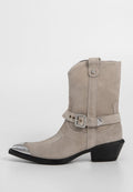 Graue Wildleder-Stiefelette mit silberner Zehenkappe, dekorativer Naht und einem metallisch akzentuierten Gürtel-Detail um den Knöchel. Schwarzer Absatz.