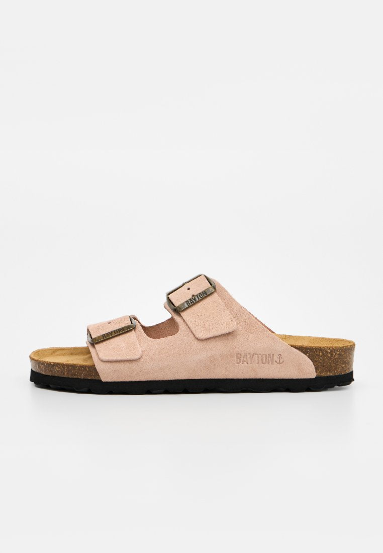 Beige Wildleder-Slide-Sandale mit zwei verstellbaren Metallschnallen, Korkfußbett, schwarzer Sohle und Bayton-Logo an der Seite.