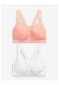 Zwei Soft-Cup-BHs mit breiten Trägern und Racerback-Design, einer in Korallenpink und einer in Weiß, flach auf einem hellen Hintergrund präsentiert.