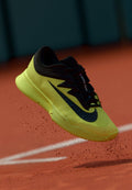 Schwarzer und neongelber Sportschuh mit strukturiertem Obermaterial und elegantem Design, das ein deutlich sichtbares Logo und eine gepolsterte Sohle aufweist.