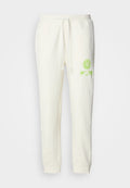 Cremefarbene Sweatpants aus Baumwollmischung mit elastischem Bund, Kordelzug und leuchtend grünem, gedrucktem Smiley-Logo auf der Vorderseite.