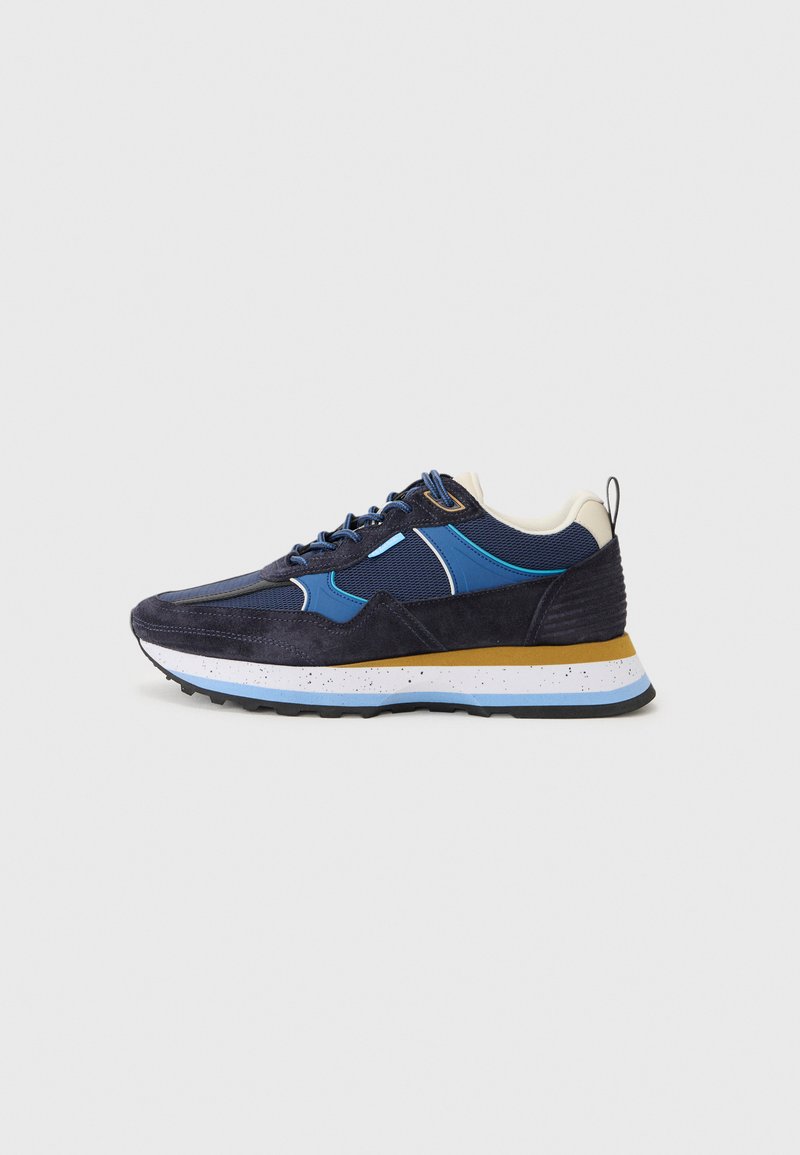 Marineblaue Sneakers aus Wildleder und Mesh-Materialien, mit weißen und hellblauen Akzenten, strukturiertem Gummisohle und einem gelben Streifen auf der Mittelsohle.