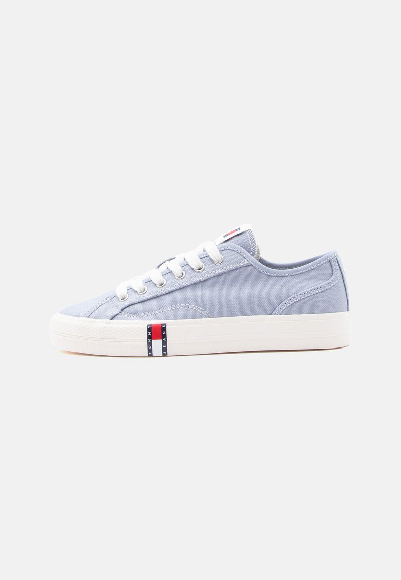 Hellblauer Canvas-Sneaker mit niedrigem Schaft, weißen Schnürsenkeln und Sohle, mit einem kleinen roten, weißen und blauen Tommy Jeans Logo an der Seite.