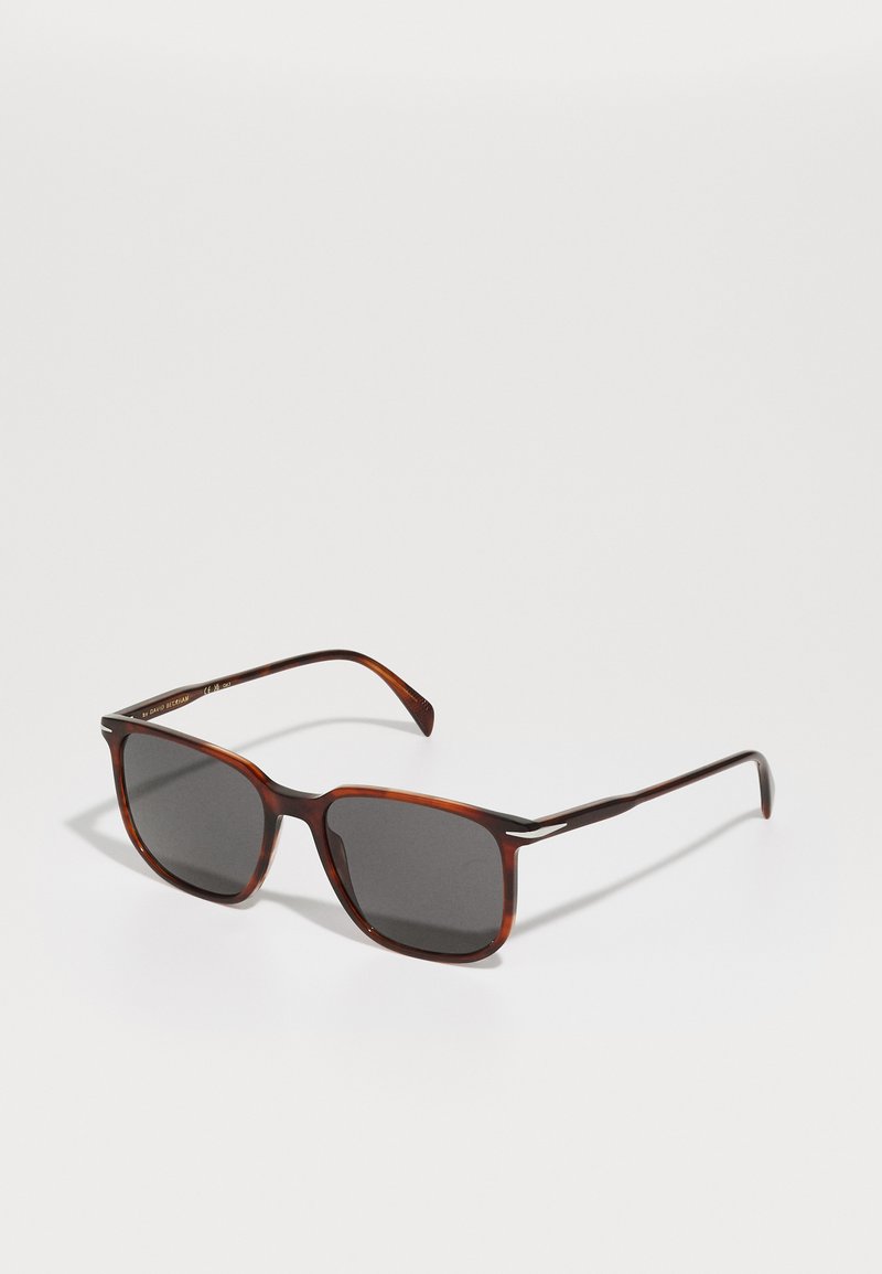 Braune Schildpatt-Sonnenbrille mit quadratischer Form, dunkelgrauen Gläsern und Metallakzenten an den Bügeln. Glatte Oberfläche und elegantes Design.