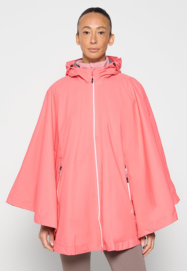 Person, der einen korallenrosa Kapuzen-Regenponcho mit Frontreißverschluss und Reißverschlusstaschen trägt und vor einem einfarbigen hellen Hintergrund steht.