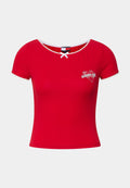 Rotes, kurzärmliges, figurbetontes T-Shirt mit rundem Ausschnitt, Spitzenbesatz und einem Herzen sowie dem aufgestickten "tommy girl"-Logo auf der Brust.