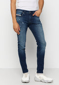 Schlanke, dunkelblaue Jeans aus Denim mit verwaschenen Details, kontrastierenden Nähten und einem Fünf-Taschen-Design, kombiniert mit weißen Sport-Schuhen.