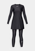Schwarz sportliches Kleid mit langen Ärmeln und rundem Ausschnitt, kombiniert mit schwarzen, figurbetonten Leggings. Ausgestattet mit einem weißen Nike-Logo auf der Brust und dem Bein.