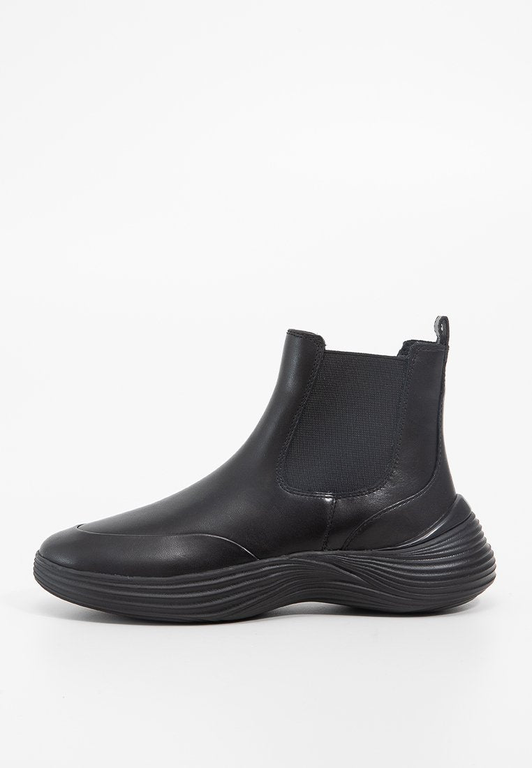 Schwarze Knöchelstiefel aus glattem Leder-Obermaterial, mit elastischen Seitenpaneelen und einer konturierten Gummisohle mit strukturierten Rillen.