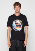 Mann trägt schwarzes T-Shirt mit farbiger, kreisförmiger Grafik eines Haifischmauls und dem Text „PS Paul Smith 1970 Satisfaction Guaranteed.“