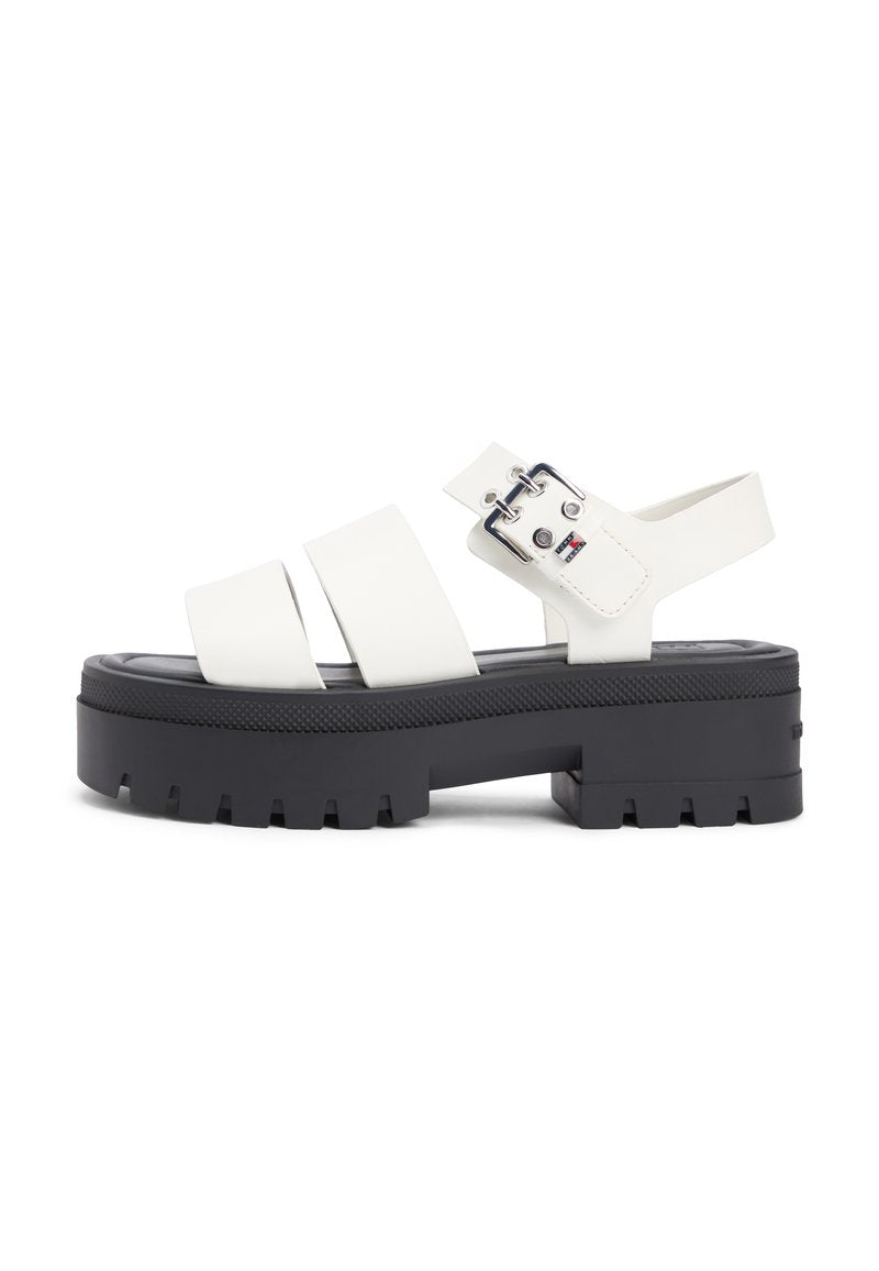Weiße Plateau-Sandalen mit drei breiten Riemen, schwarzer massiver Sohle und silberner Schnallenverzierung. Glatte Textur mit leichtem Glanz.
