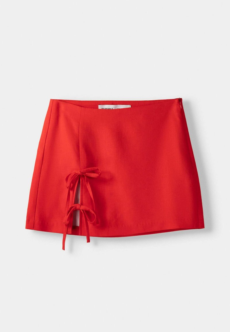 Roter Rock mit geradem Schnitt, seitlichen Bindebändern und glatter Textur. Entworfen im einfachen, minimalistischen Stil ohne Muster.