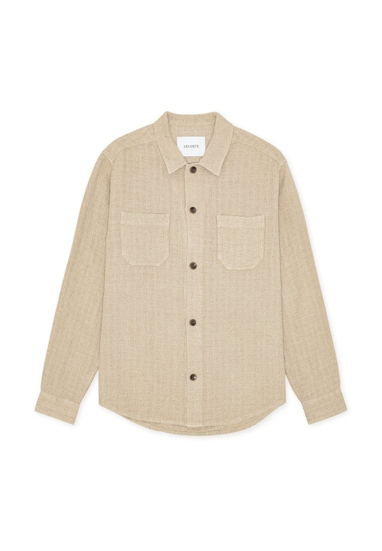 Beige Hemd zum Zumachen aus strukturiertem Stoff mit Kragen, zwei Brusttaschen und braunen Knöpfen. Gerader Saum und lange Ärmel.