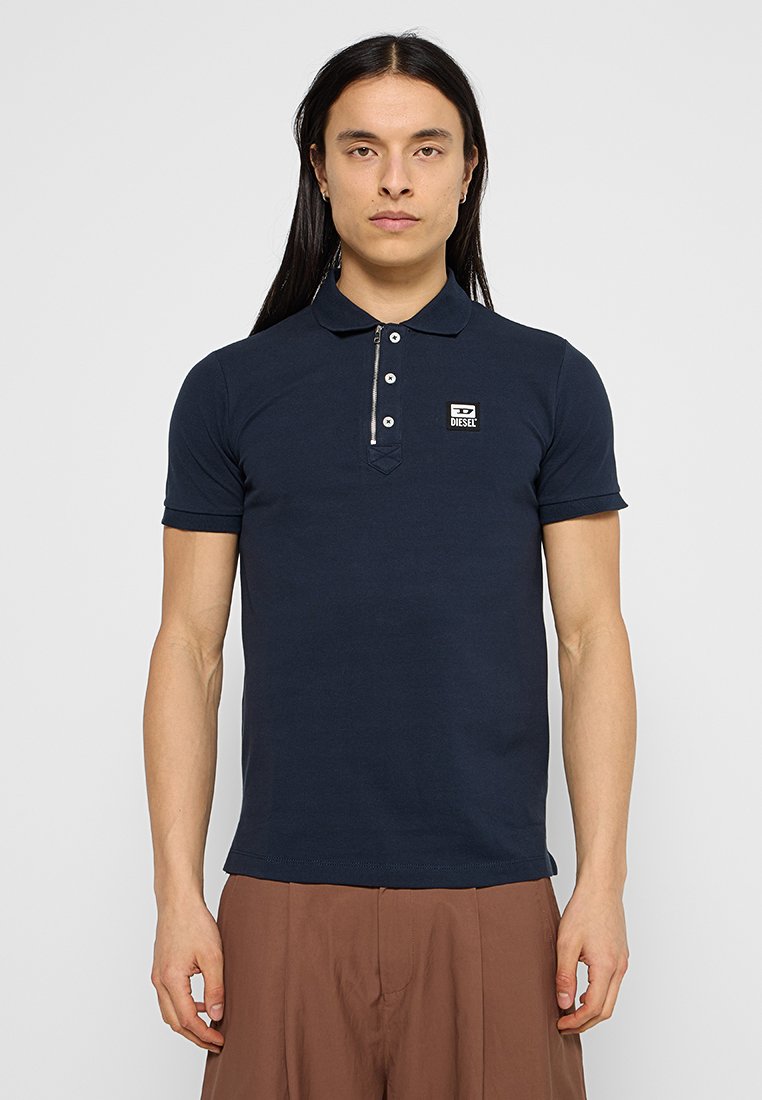 Marineblaue Polo-shirt mit Kragen, ausgestattet mit einem Reißverschluss, drei Knöpfen und einem kleinen Logolabel auf der Brust. Kurzärmlig, taillierte Passform.
